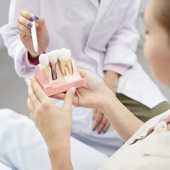 A dentist pointing at a model of a dental implant